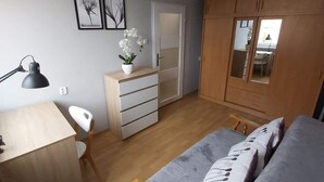 Ett sovrum med en säng, ett skrivbord, en stol, en garderob och en takfläkt.