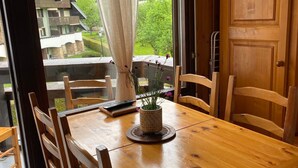 A wooden dining table with chairs, a vase with flowers, and a window with curtains. - 2-room apartment with pets allowed, balcony and garage (Samoëns)