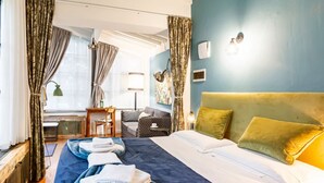 A hotel room with a bed, a desk, a chair, and a window with curtains.