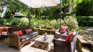 Un patio exterior con mobiliario de mimbre, una mesa y una silla colgante.