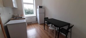 A small kitchen with a refrigerator, microwave, sink, and a table with two chairs. - Nice apartment close to Leipzig (Zeitz)