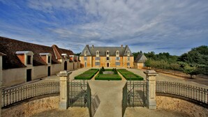 A large, historic building with a symmetrical facade, a central courtyard with a geometric garden, and a traditional iron gate. - Stunning chateau, built in 1611, beautifully renovated, furnished and equipped. (Saint-Geyrac)