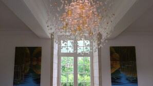 A room with a large window, a chandelier, and two paintings on the walls. - Stunning chateau, built in 1611, beautifully renovated, furnished and equipped. (Saint-Geyrac)