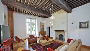 A spacious living room with a wooden ceiling, a fireplace, leather sofas, and a television. - Stunning chateau, built in 1611, beautifully renovated, furnished and equipped. (Saint-Geyrac)