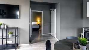 A modern hotel room with a bed, bedside table, and a TV mounted on the wall. - The New Post Office (Vestmannaeyjar)