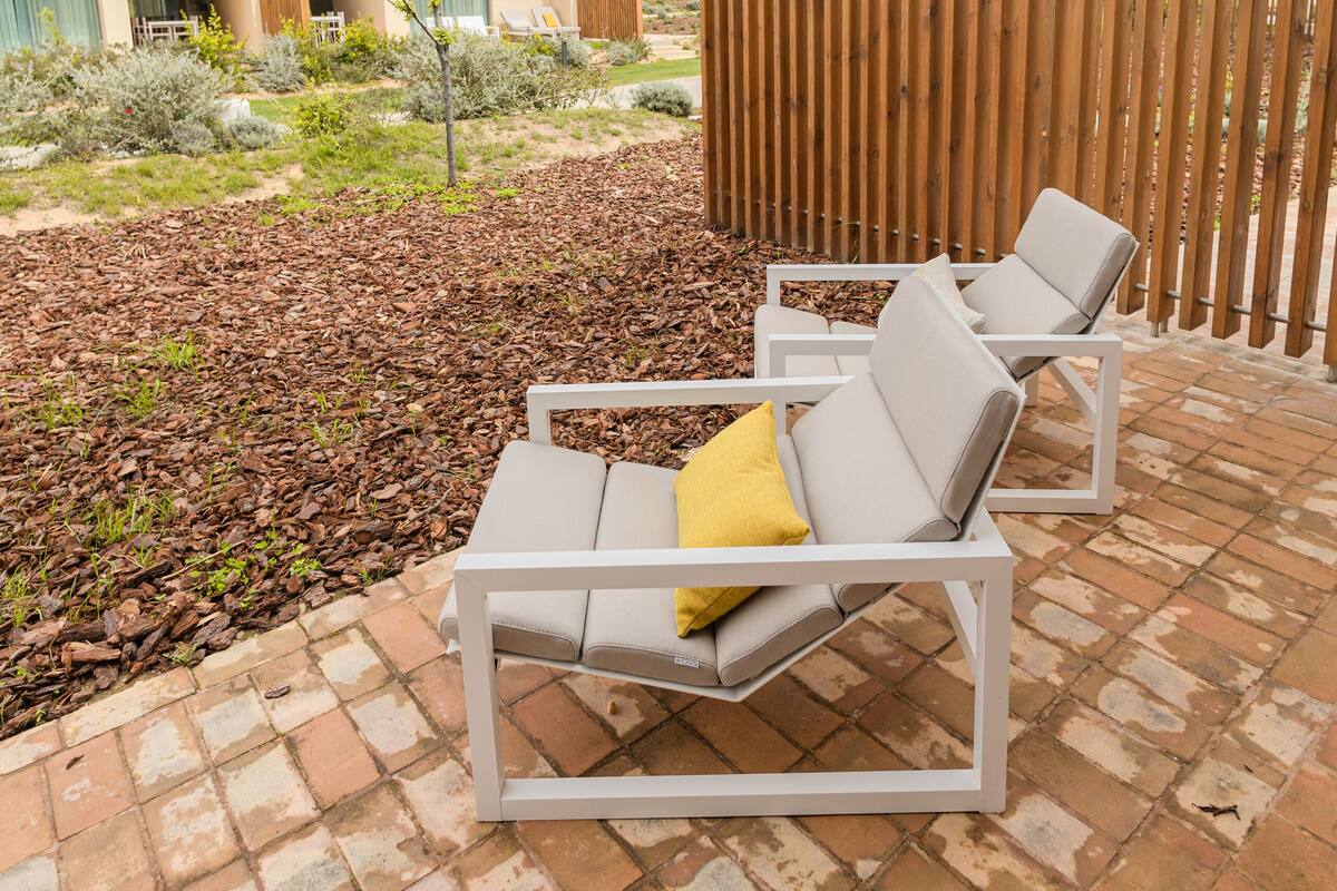 Une terrasse avec deux chaises longues blanches, une clôture en bois et, au fond, un immeuble doté de balcons.