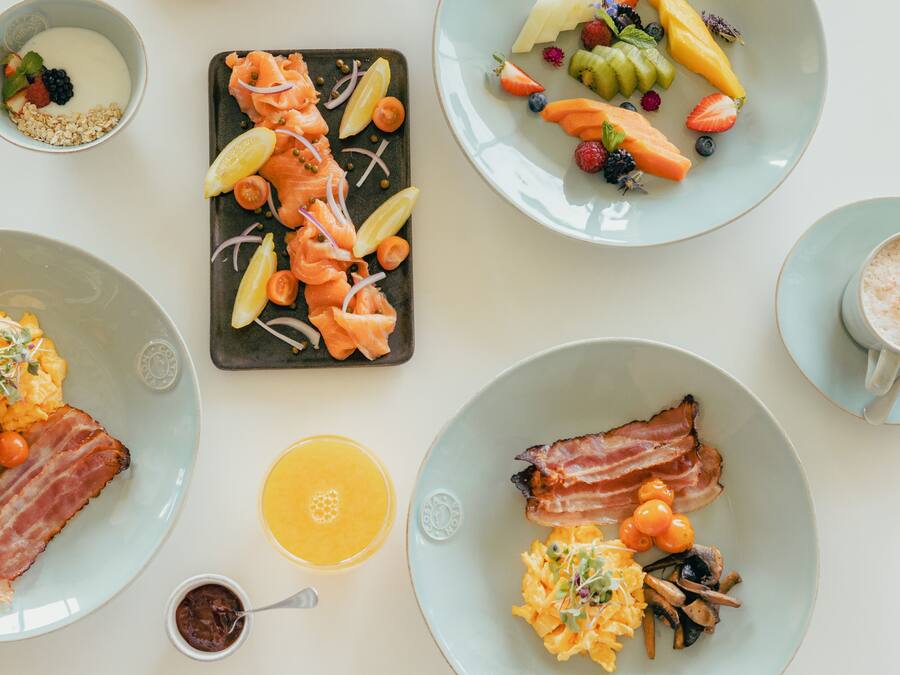 A breakfast buffet with various dishes including eggs, bacon, and fruits.