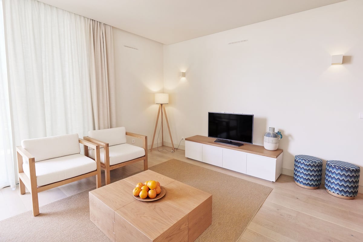 Un salon moderne comprenant un canapé, une table basse, un téléviseur et des objets de décoration.