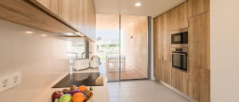 A modern kitchen with wooden cabinets, a black countertop, and a fruit bowl.