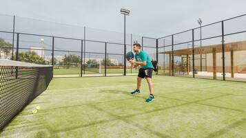 A tennis court with a net, a player, and a ball.