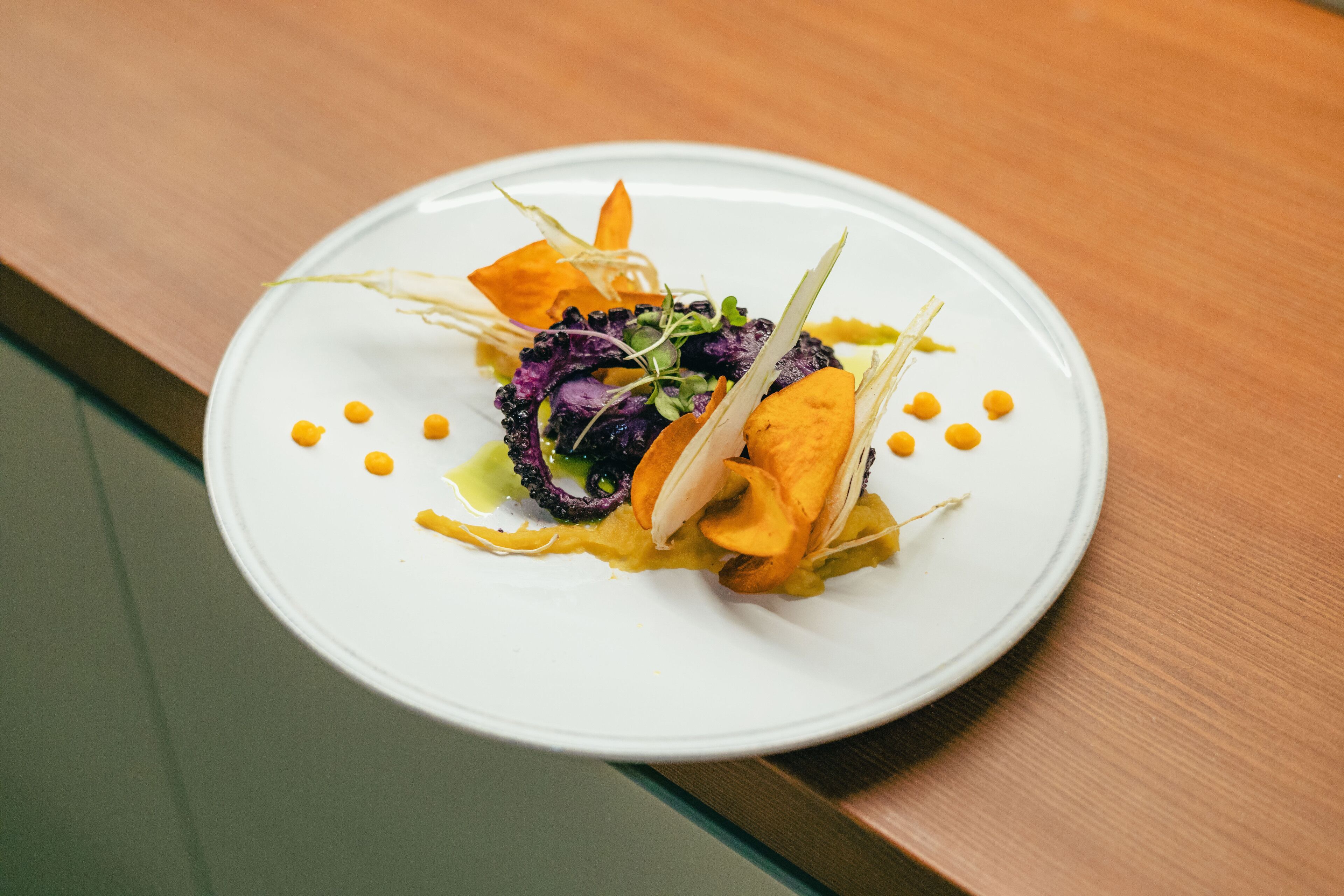 Une assiette blanche sur laquelle se trouve un plat coloré, le tout posé sur une table en bois.