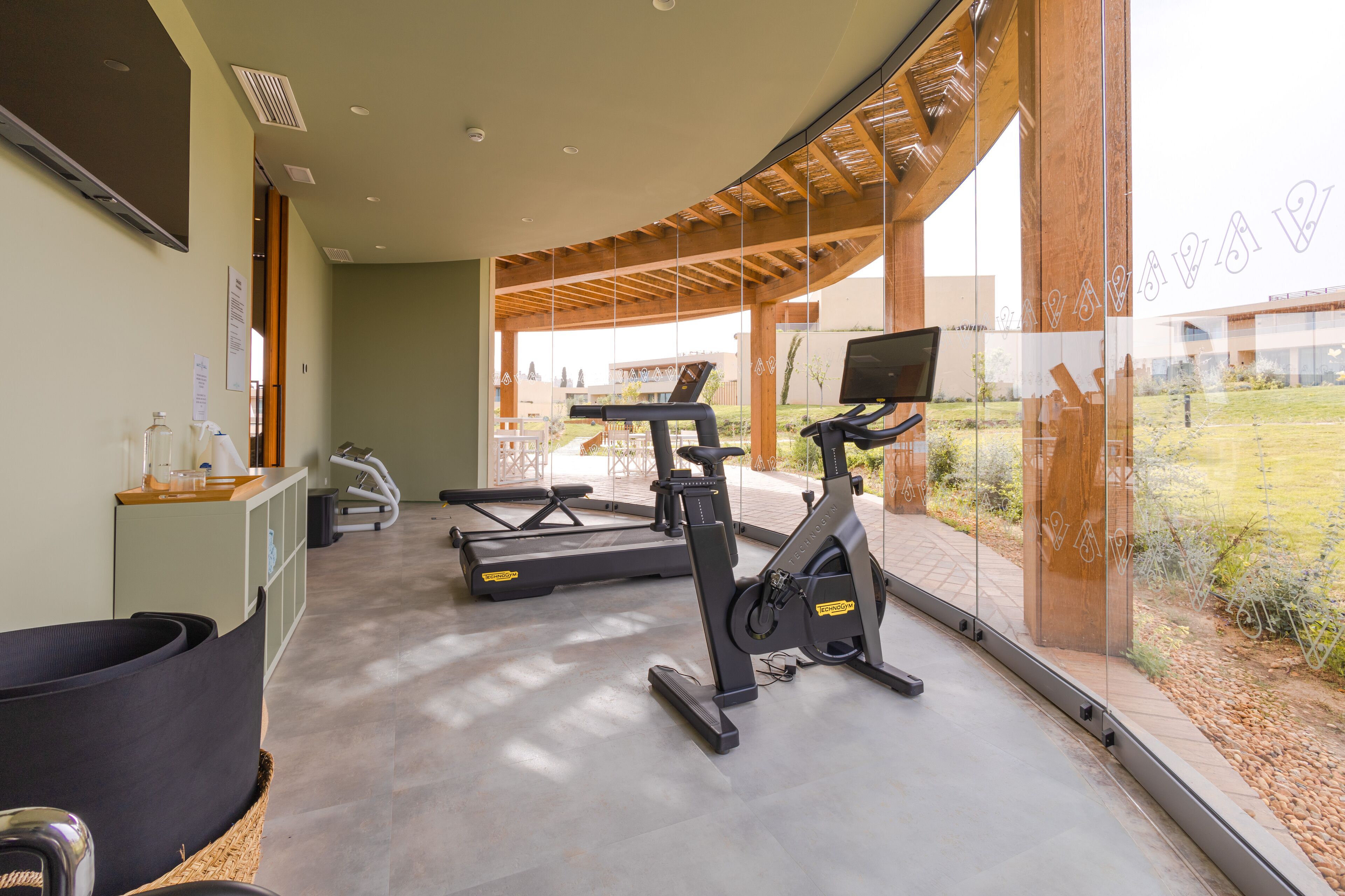 A modern gym with cardio equipment, a reception desk, and a view of the outdoors.