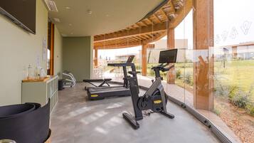 A modern gym with cardio equipment, a reception desk, and a view of the outdoors.