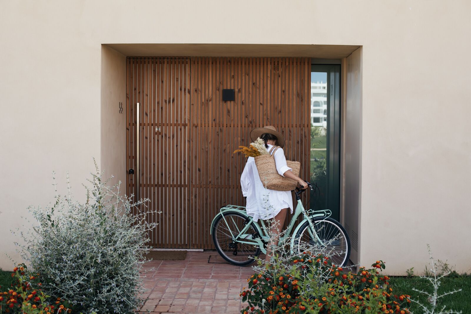 A person standing next to a wooden door with a bicycle.