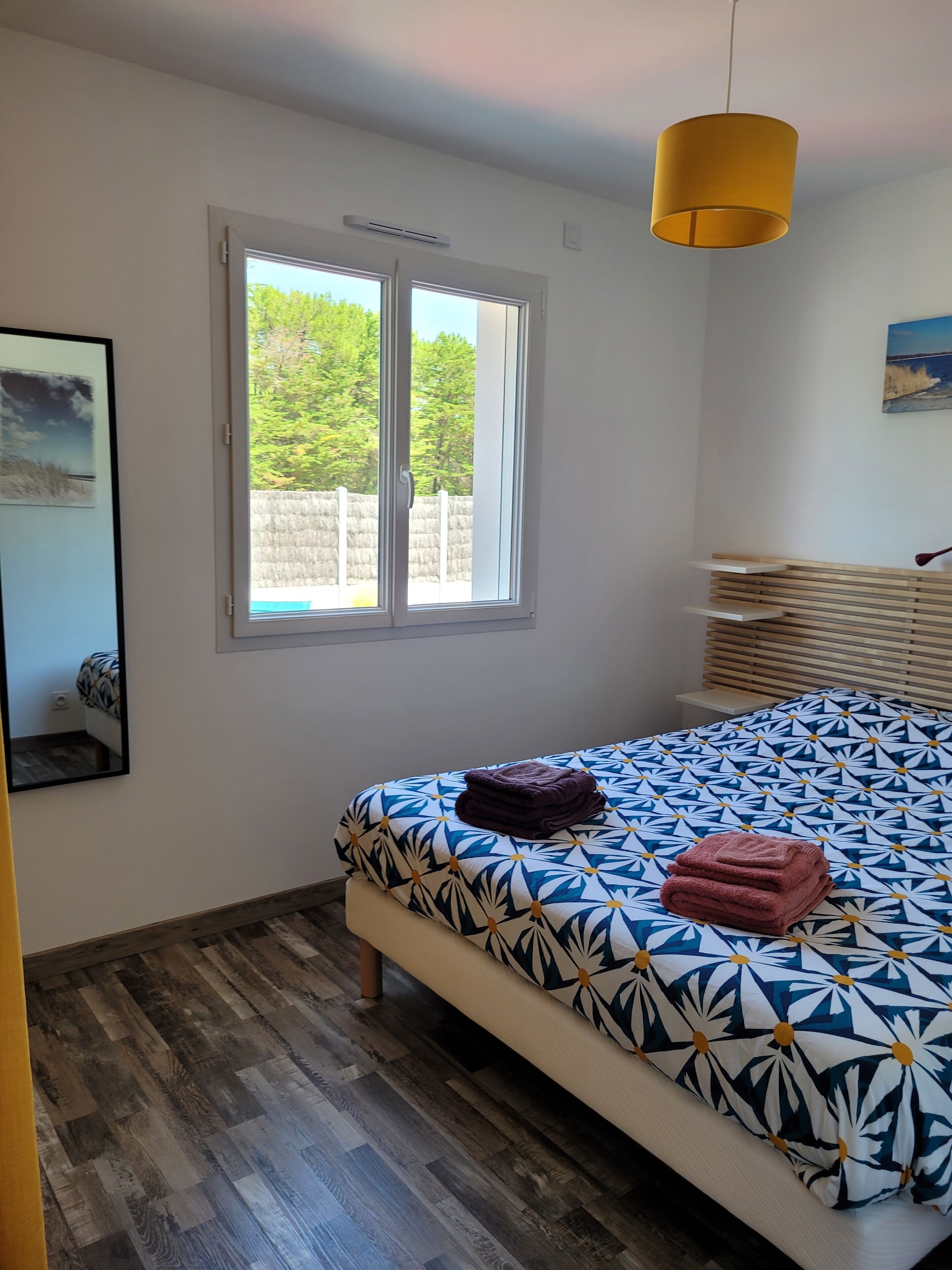 Un dormitorio con cama, ventana y lámpara colgante.
