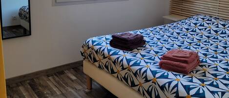 Un dormitorio con cama, ventana y lámpara colgante.