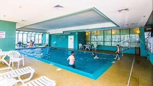 Ein Hallenbad mit deutlich abgegrenzten Bahnen, Liegestühlen und Blick ins Freie.