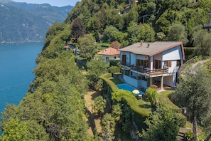Una casa de dos pisos con balcón, piscina y vista al mar.