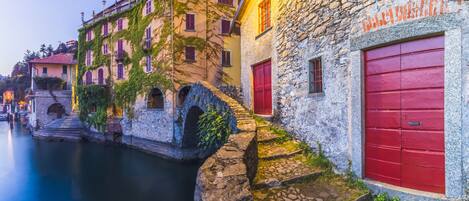 A stone building with a red door and a stone bridge over a canal.