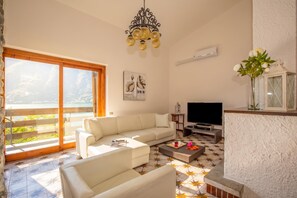 A living room with a sofa, a coffee table, a TV, and a large window with a view.