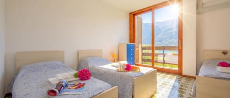 Ein Hotelzimmer mit zwei Betten, einem kleinen Tisch mit einem Frühstücksbrett, einem Fenster mit Blick auf die Berge und einer Klimaanlage.