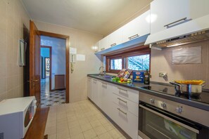 A kitchen with a stove, oven, and a window. - Villa Marilyn (Nesso)