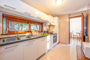 A modern kitchen with white cabinets, a stainless steel sink, and a window overlooking greenery.