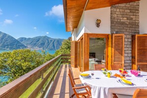 Balcón con una mesa dispuesta para comer, con vistas a un paisaje montañoso.