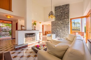 Un espacio habitable amplio con chimenea, una pared de acento de piedra y un ventanal grande.