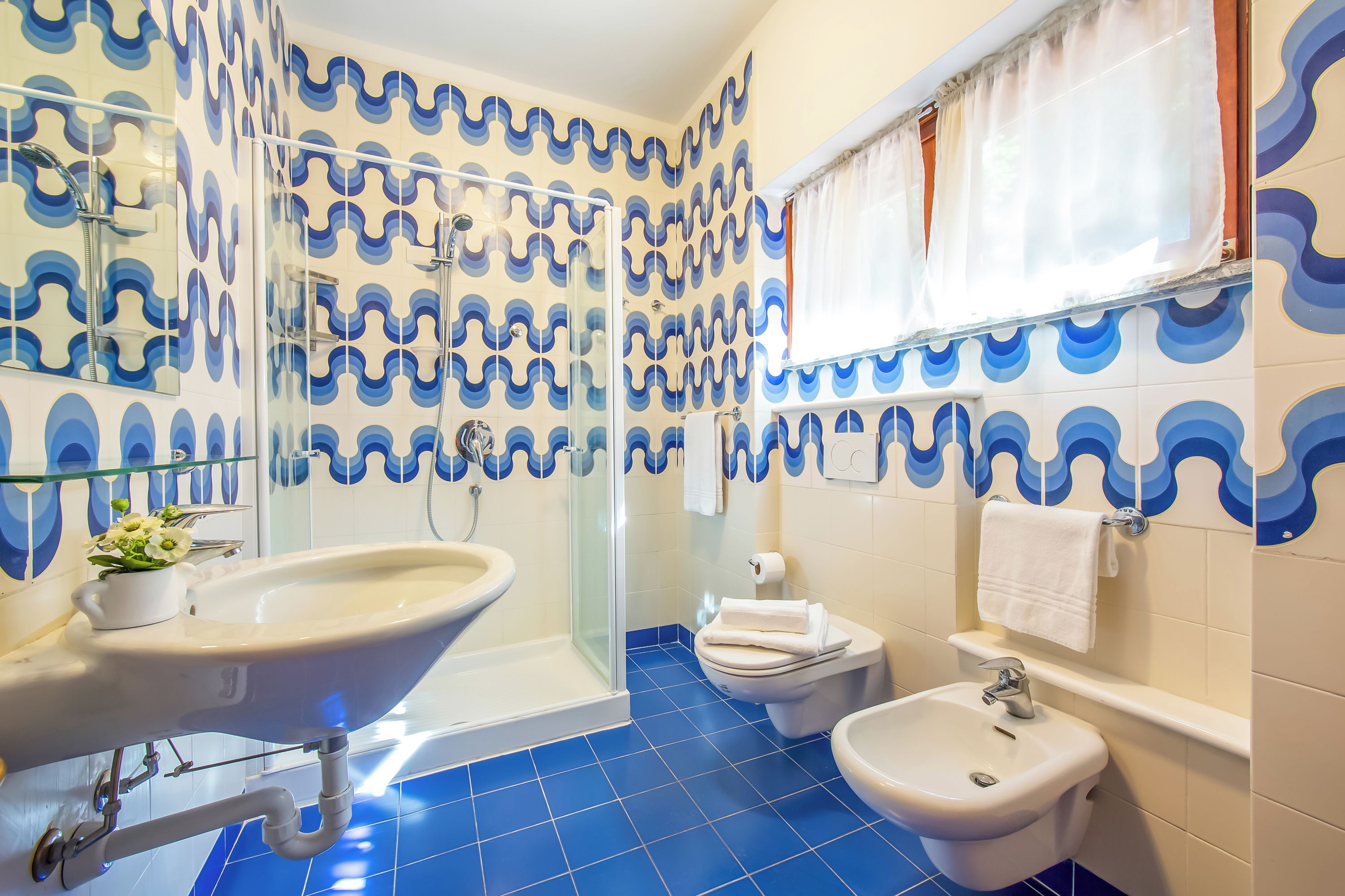 A bathroom with a sink, bidet, and shower.