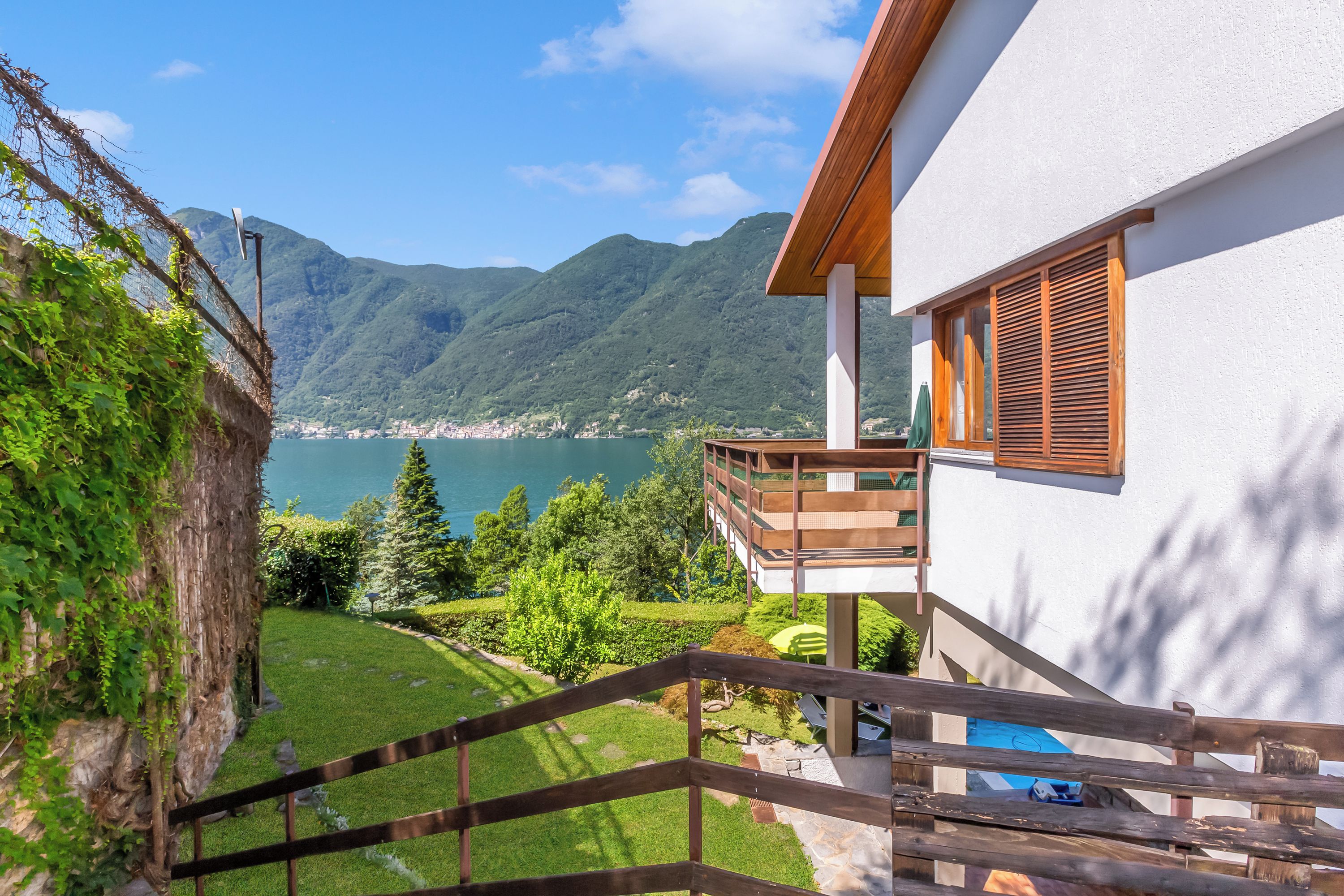 A modern house with a balcony overlooking a lake and mountains.