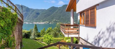 Une maison moderne dotée d’un balcon donnant sur un lac et des montagnes.