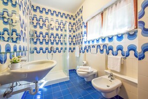 Un baño con lavamanos, bidé y ducha.