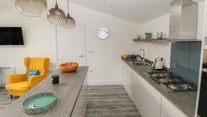A modern kitchen with a grey countertop, stainless steel appliances, and pendant lighting. - Summerhouse (Tenby)