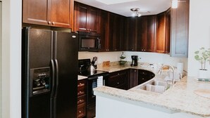 A kitchen with dark wooden cabinets, a black refrigerator, a microwave, a sink, and a countertop with a kettle. - Stunning townhouse on quiet street in Springfield! (Jacksonville)