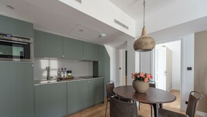 Een moderne keuken met een inbouwoven, een spoelbak en een eethoek met een ronde tafel en stoelen.