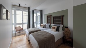 Een slaapkamer met twee bedden, een rieten stoel en een gevlochten vaas op een nachtkastje.