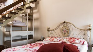 Ein Schlafzimmer mit einem Bett, einem Nachttisch, einer Kommode und einer Treppe.
