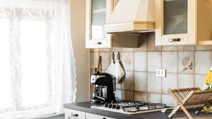 Eine Küche mit Gasherd, Kaffeemaschine und einem hölzernen Wäscheständer.