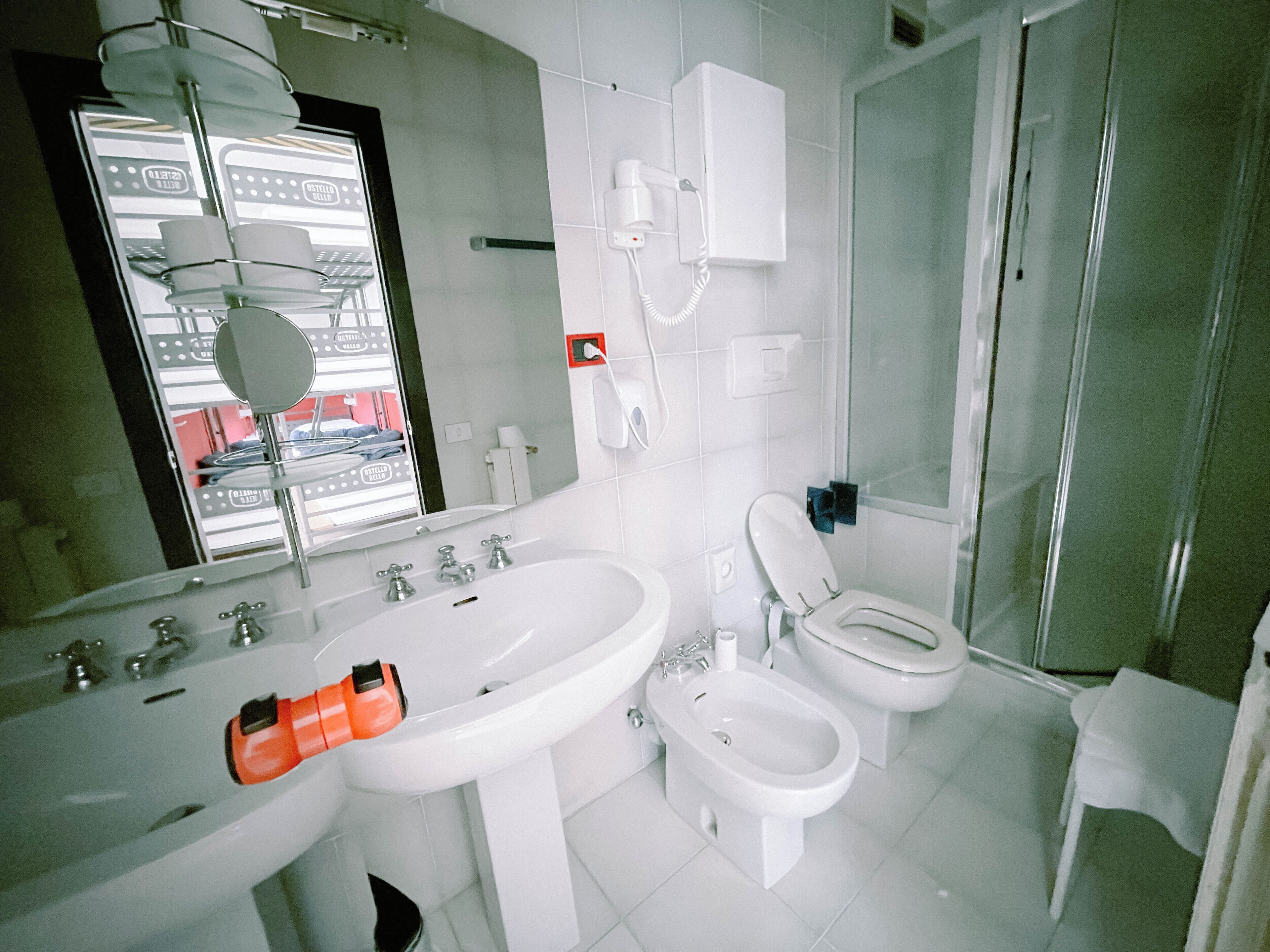 A bathroom with a sink, toilet, bidet, and a shower area.