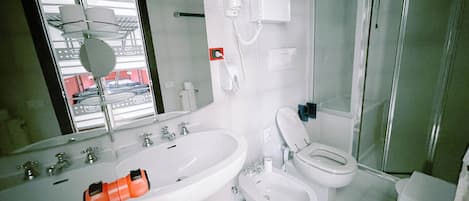 A bathroom with a sink, toilet, bidet, and a shower area.
