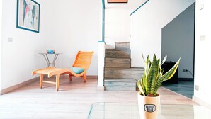 A modern interior with a wooden chair, a small table, a potted plant, and a staircase. - Ostello Bello Genova (Genoa)