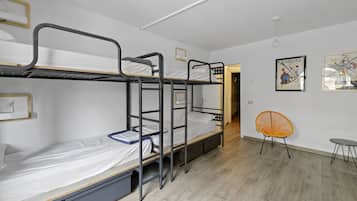Ein Schlafsaalzimmer mit Etagenbetten, einem kleinen Tisch und einem Stuhl.
