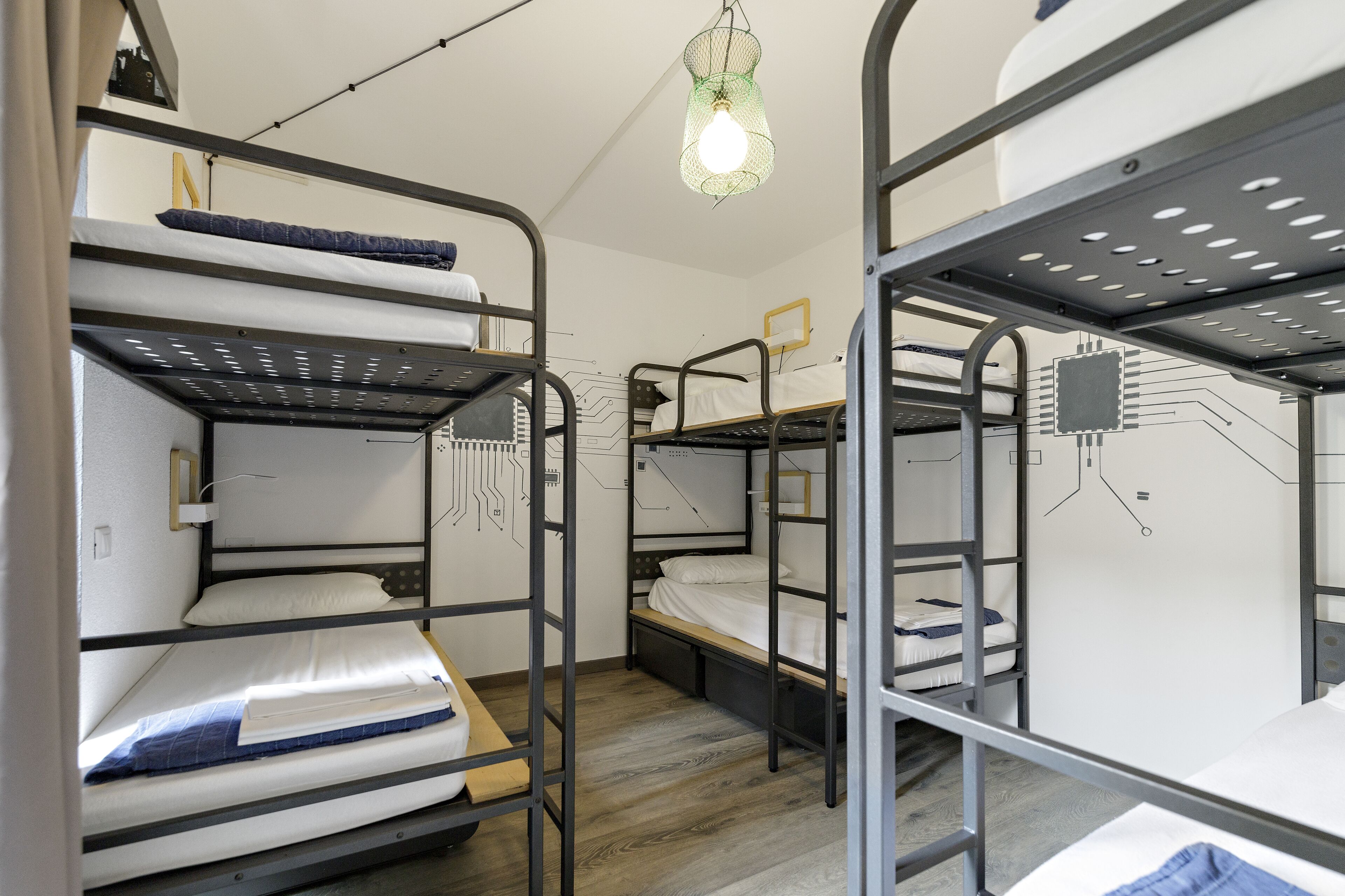 Ein Schlafsaalzimmer mit Etagenbetten, einem Schreibtisch und einer Pendelleuchte.