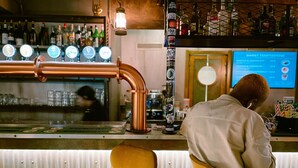 A bar with a copper pipe, a person seated, and a menu display. - Ostello Bello Genova (Genoa)