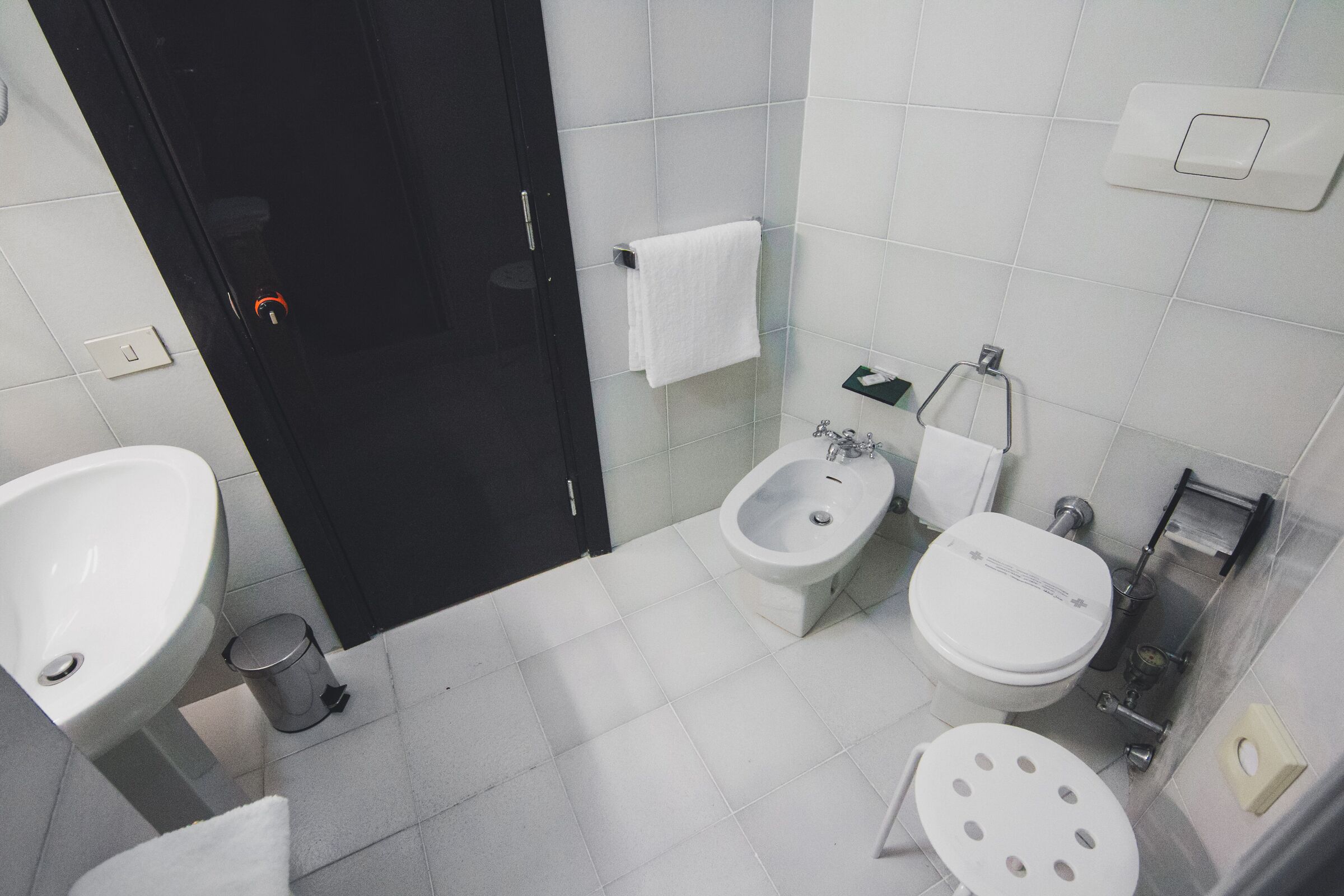 Un bagno con lavandino, bidet, WC e cestino.