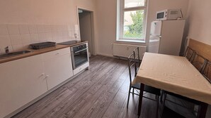 A kitchen with a wooden countertop, white cabinets, an oven, a microwave, and a window with a view of greenery.