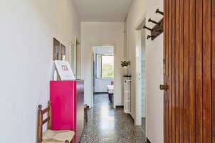 A hallway with a wooden door, a pink refrigerator, and a chair.