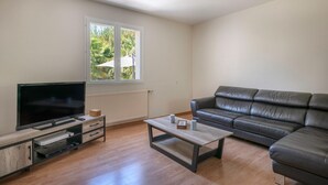 A living room with a flat-screen TV, a leather sofa, and a coffee table. - Superb house for 8 in Crach with swimming pool (Crach)