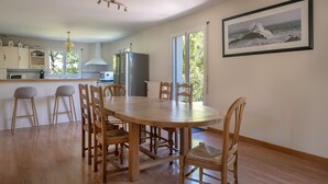 A spacious kitchen with wooden cabinets, a dining area with a wooden table and chairs, and a large window offering a view of the outdoors. - Superb house for 8 in Crach with swimming pool (Crach)